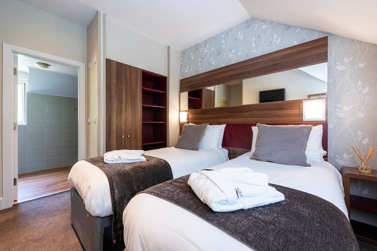 Twin beds with neatly folded spa robes in a Spa Break apartment.
